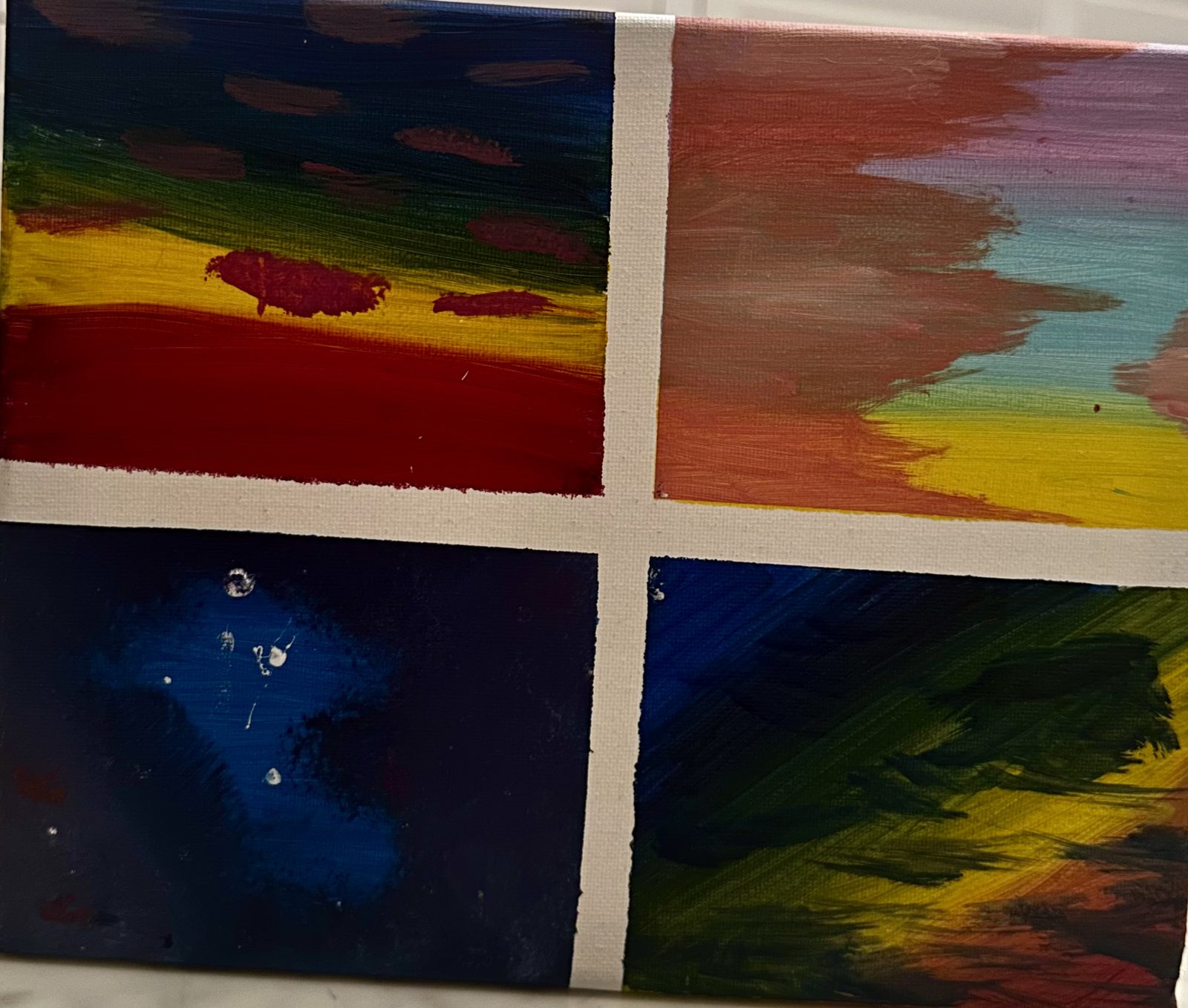 A small canvas painted as four separate skies, split by bare white canvas in a cross. Top left is deep blue over green and red. Top right is coral and turquoise fading down into yellow. Bottom left is dark night blue with white paint flecks. Bottom right is dark green and gold.